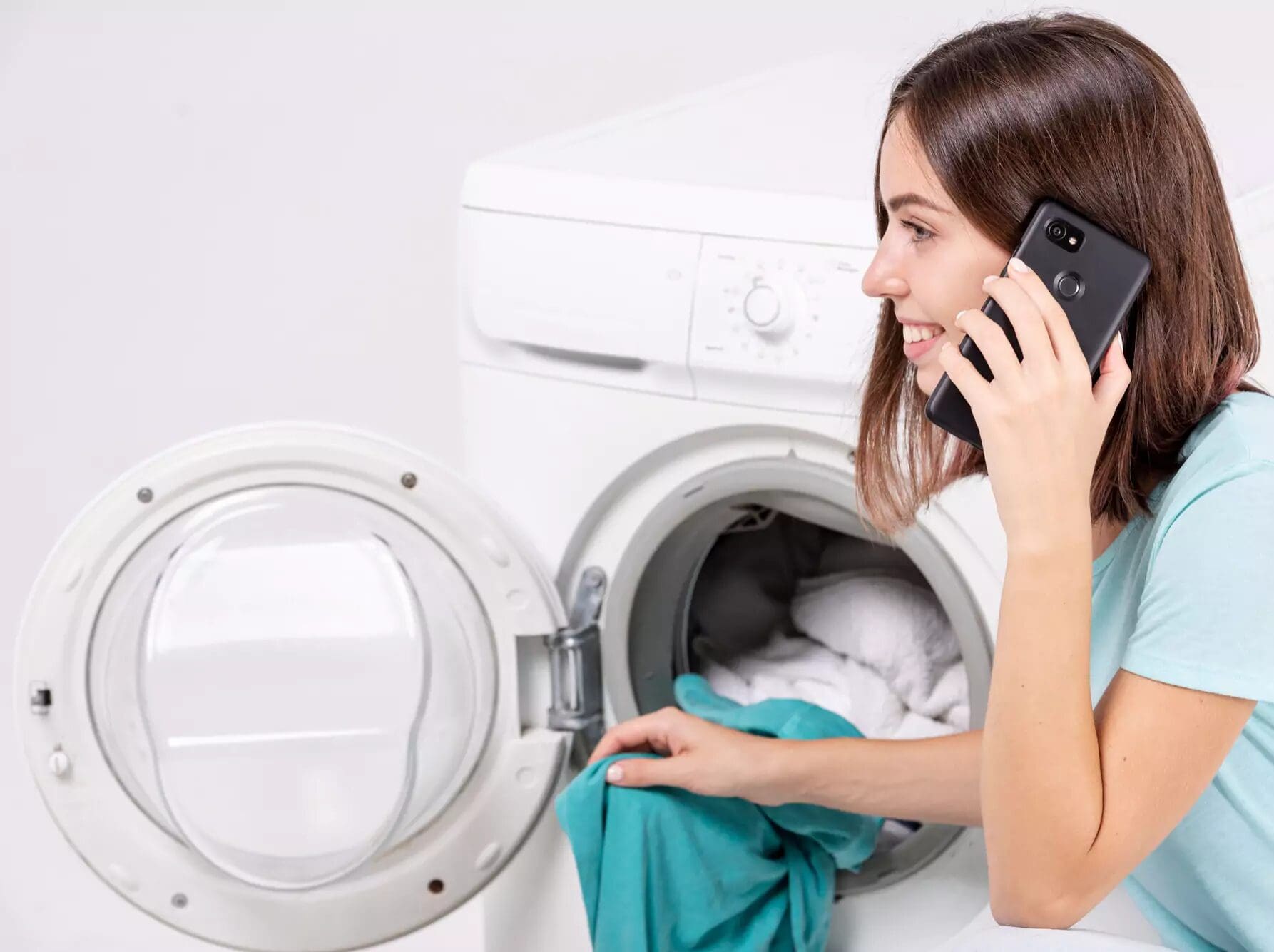 Woman talking in phone while doing laundry