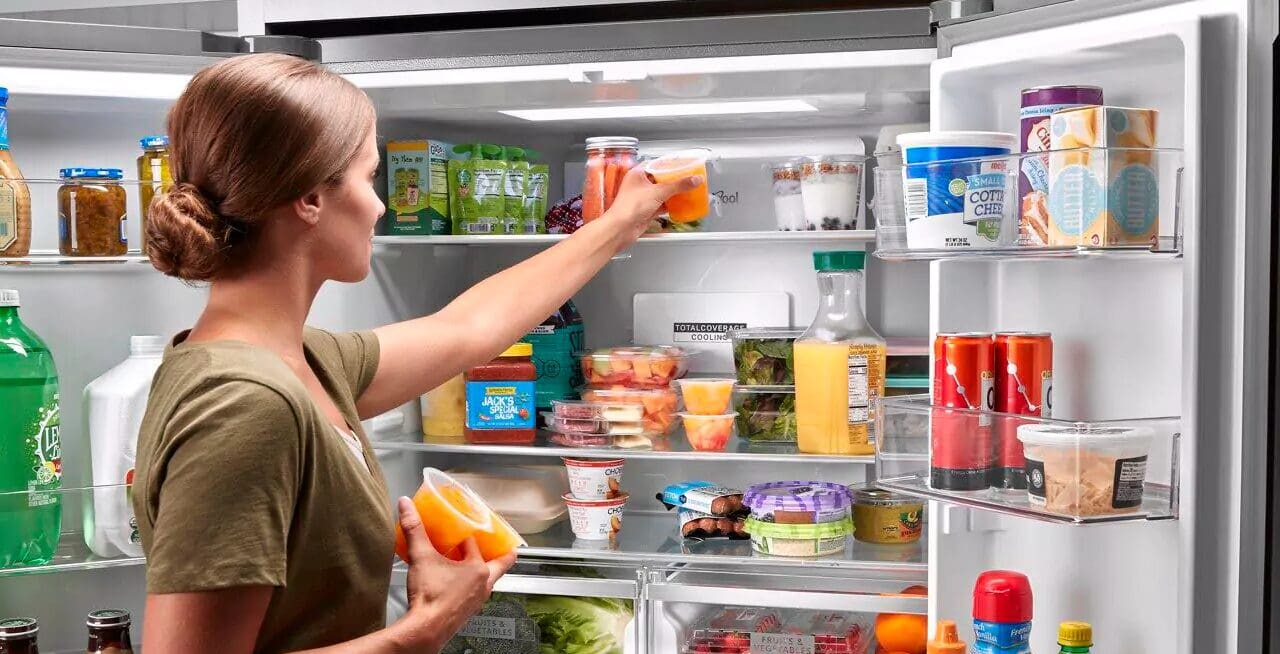 open refrigerator woman putting food