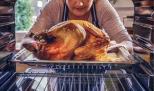 woman taking turkey out of stove oven