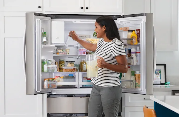 woman taking out food from frigidaire refrigerator